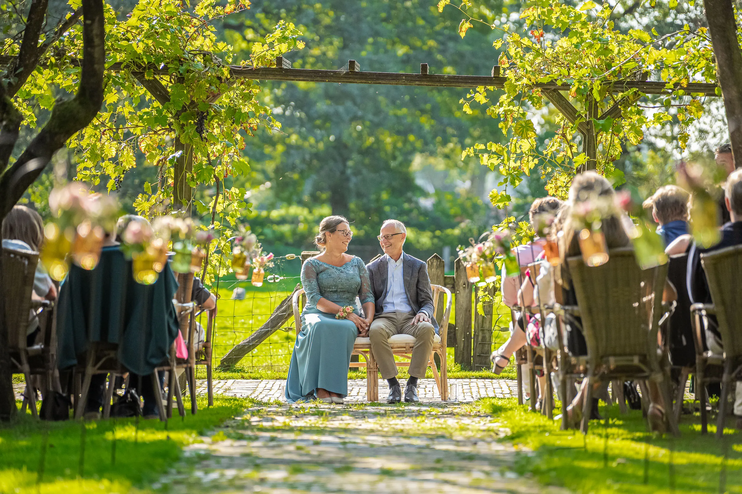 Ben en Patricia onder de pergola, omringd door gasten