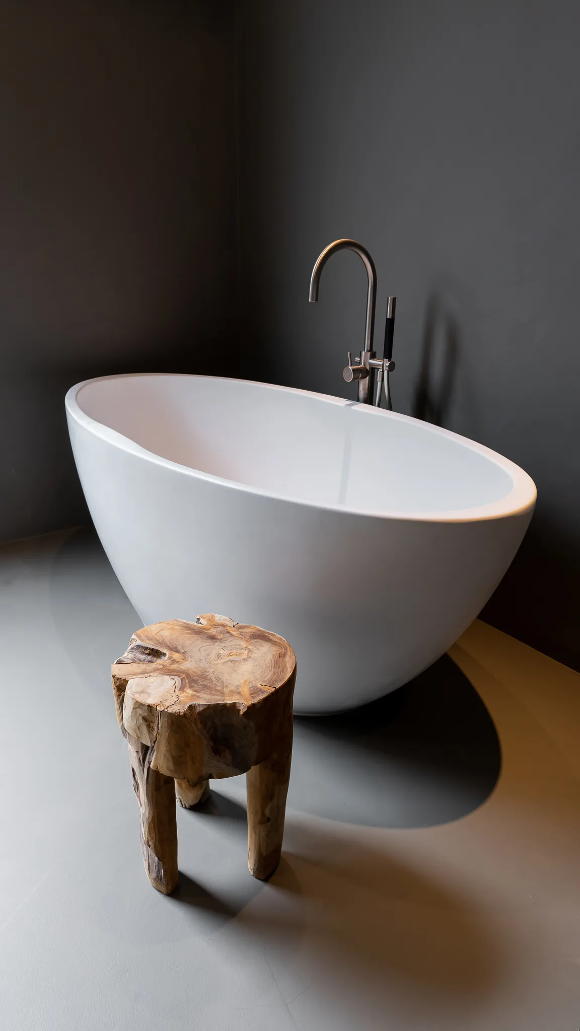 Vrijstaand bad met een houten krukje