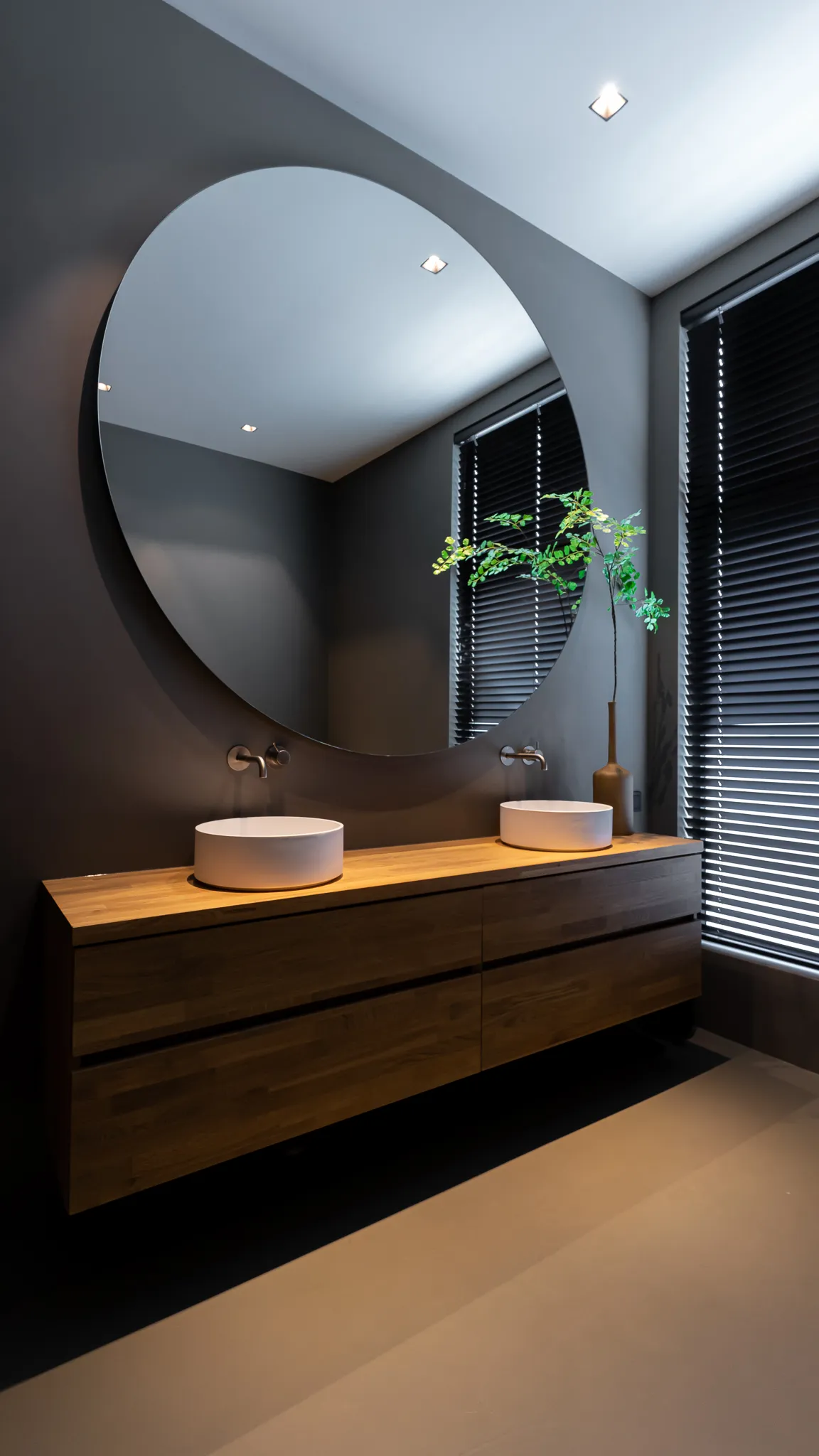 Badkamer met ronde spiegel en houten badmeubel