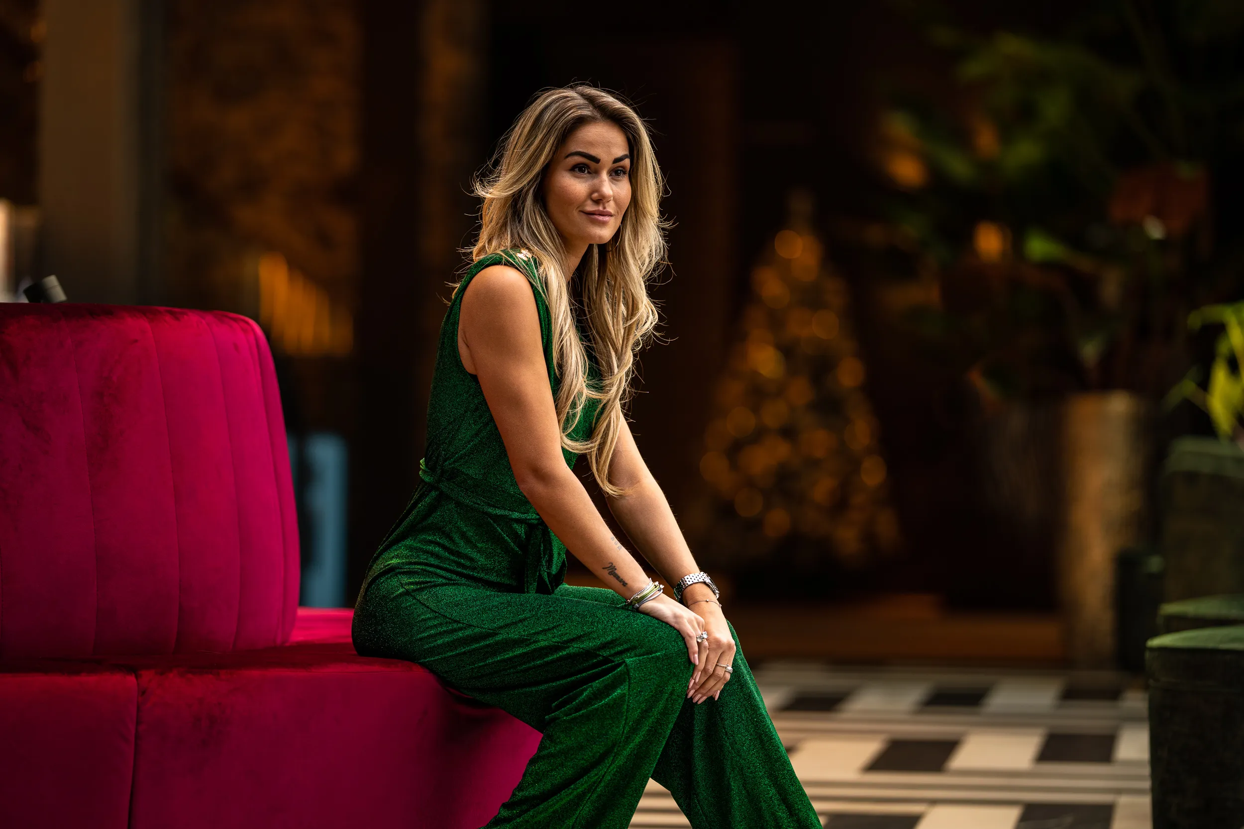 Model in groen op een rode bank in kerstsfeer