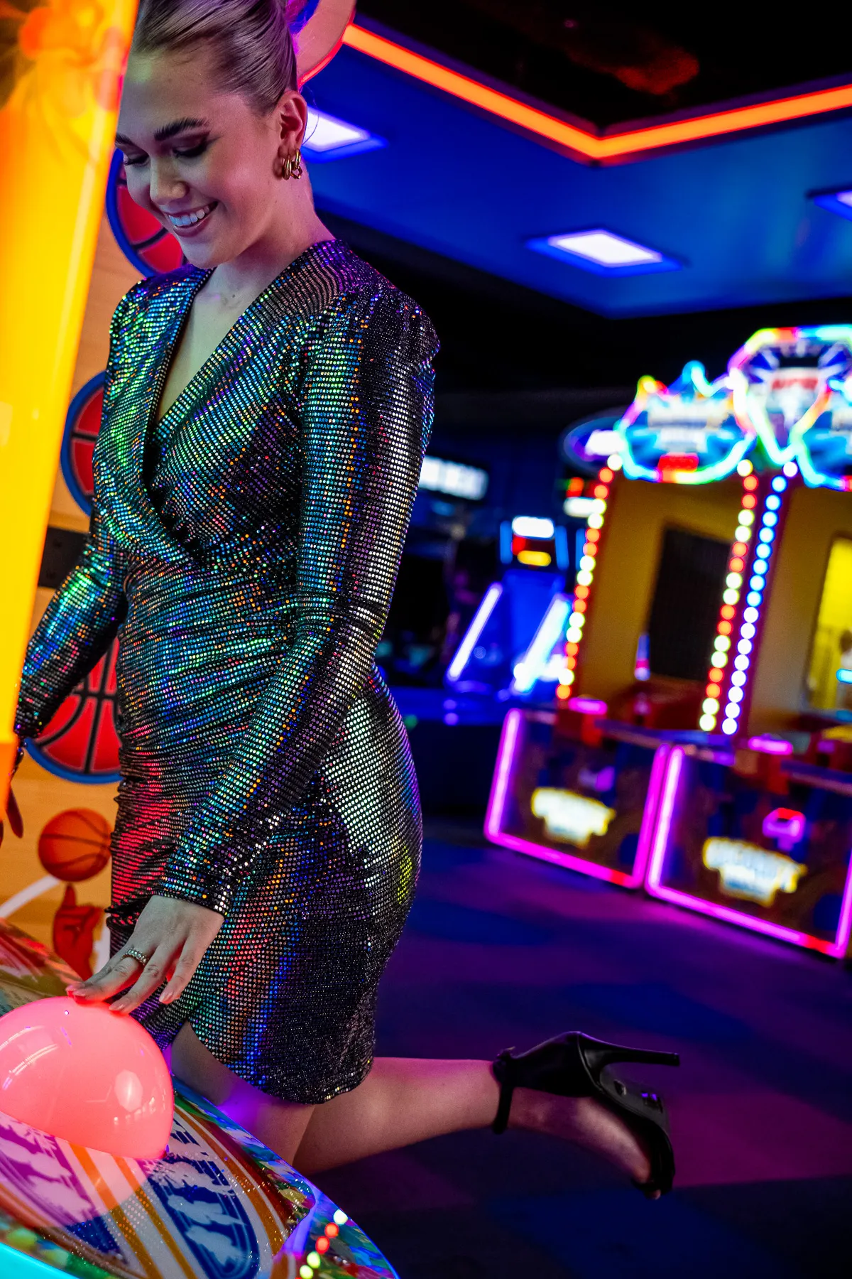Model in glitterjurk bij een arcadekast