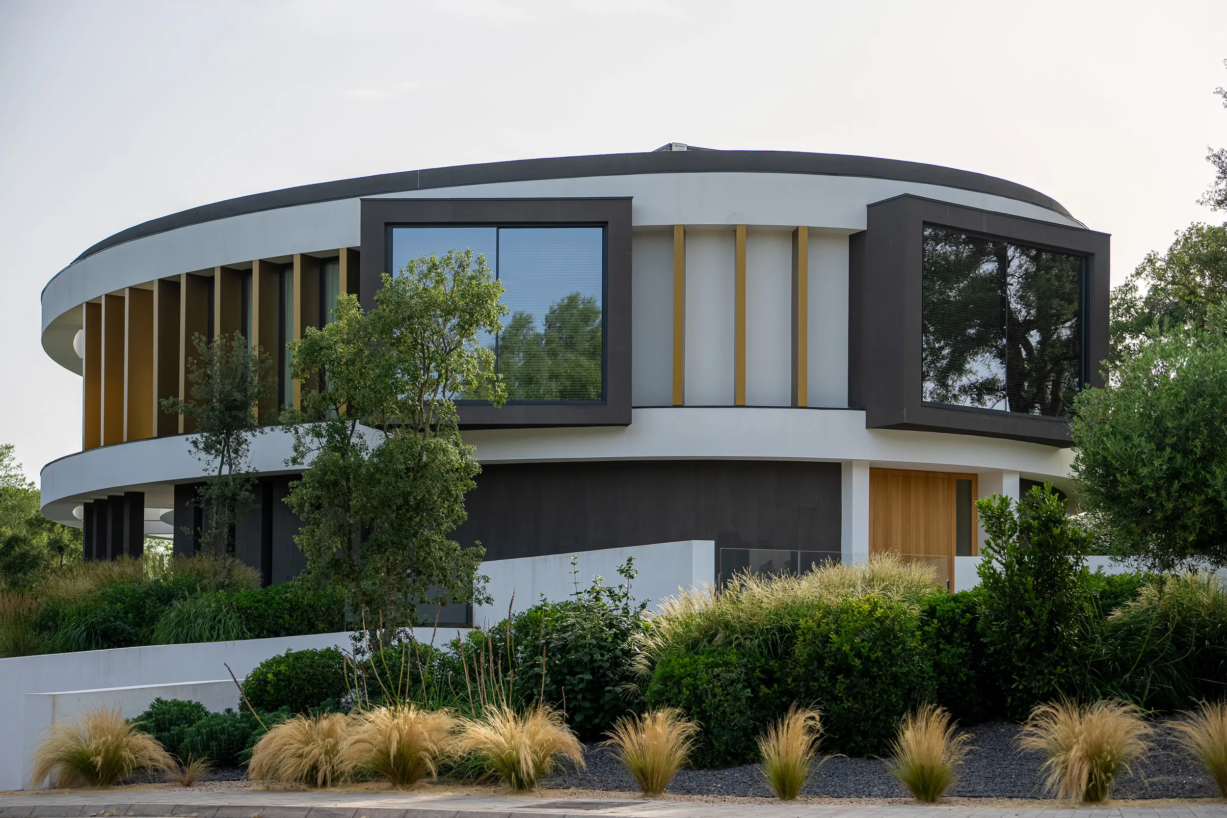 Ronde moderne villa met siergrassen in de tuin